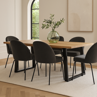 Dining table with black dining chairs in a room with an arch window and a beige rug
