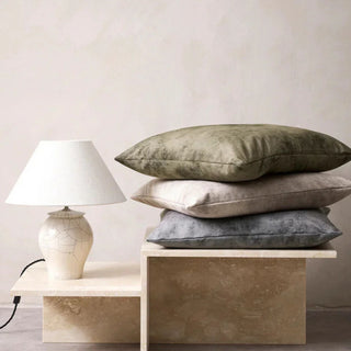 three cushions stacked on a marble display stand with a lamp