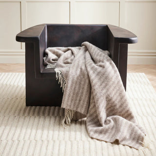 Throw on a wooden chair in a room with a beige carpet