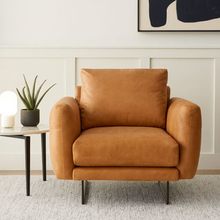 Tan leather occasional chair with a side table that has a faux plant on it