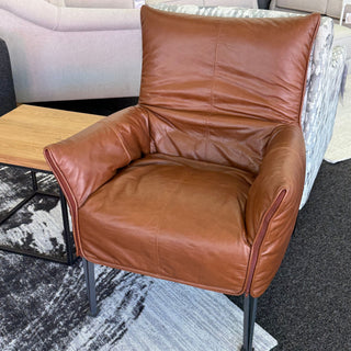 Brown leather armchair in a room with a coffee table and rug.