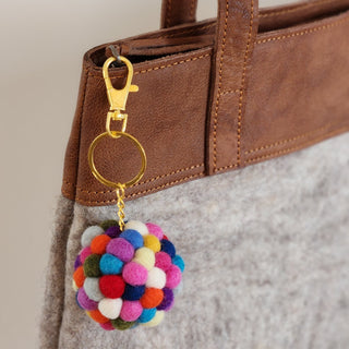 Colourful felt ball keyring hanging from a brown handbag
