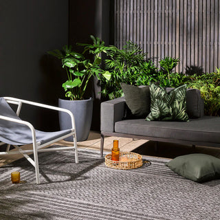 Outdoor seating area with a gray sofa, chair, and potted plants.
