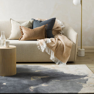 Cozy living room with a beige sofa, cushions, and a throw blanket on a dark patterned rug.