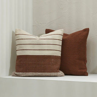 Two brown and beige patterned pillows on a white surface with a neutral background