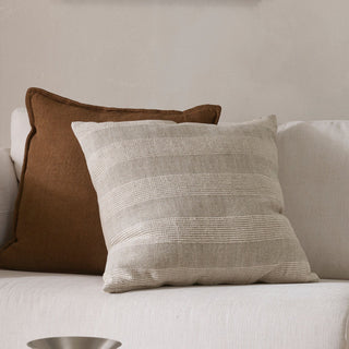 Two textured pillows on a light-colored sofa against a neutral wall.