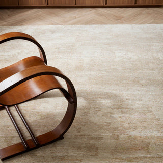 Wooden chair on a textured beige rug with wooden floor panels.