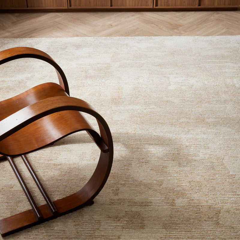 Wooden chair on a textured beige rug with wooden floor panels.