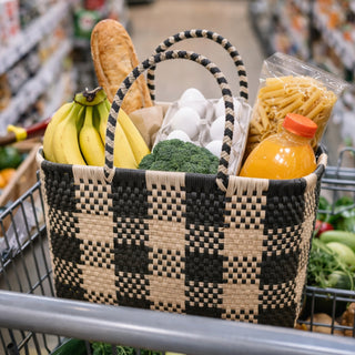 Woven grocery basket with groceries in a shopping cart at a grocery store.