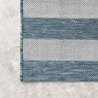 Close-up of a blue and white striped rug on a textured surface