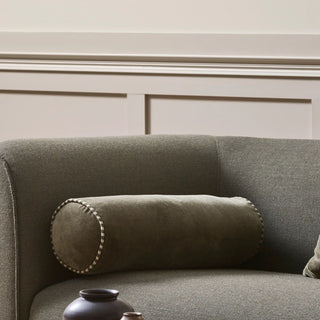 Thyme brown cushion on a gray sofa against a neutral wall.
