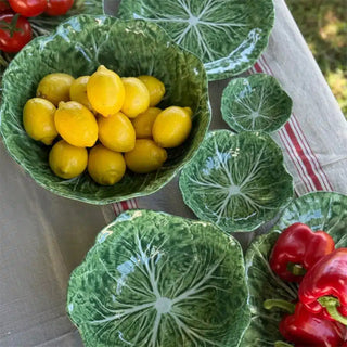 Large cabbage leaf melamine bowl filled with lemons on outdoor dining table