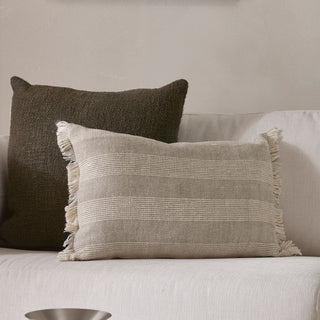 Two textured pillows on a light-colored sofa against a neutral wall.