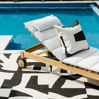 Wooden lounge chair with white and black cushions by a pool