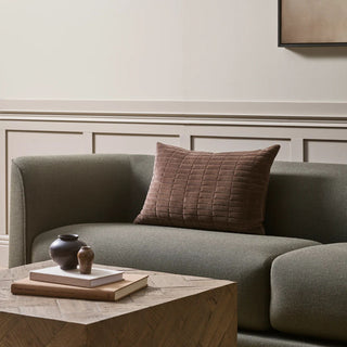 Gray sofa with a brown textured pillow in a room with decorative wall molding.