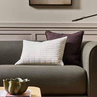 Gray sofa with white and brown pillows in a living room setting.
