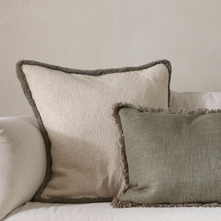 Two textured pillows with frayed edges on a neutral background