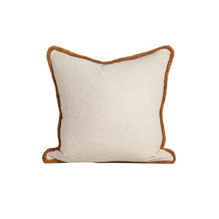 Beige pillow with brown trim on a white background