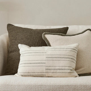 Three pillows on a sofa with a neutral background