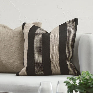 Decorative pillow with black and beige stripes on a gray sofa.