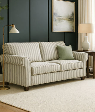 Striped sofa in a living room with a lamp, side table, and artwork.