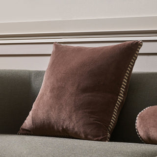 Brown pillow on a gray sofa against a neutral wall