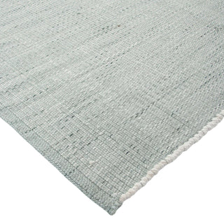 Close-up of a textured light gray rug corner on a white background
