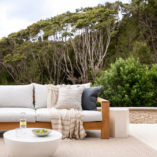 Outdoor patio with a wooden sofa, cushions, and a small table with a bottle and bowl.