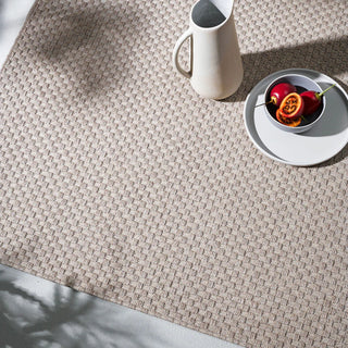 Textured beige rug with a white pitcher and plate on top