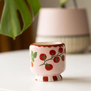 Small ceramic pot with tomato design on a white surface