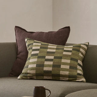 Checkered pillow on a gray sofa with a brown mug in front