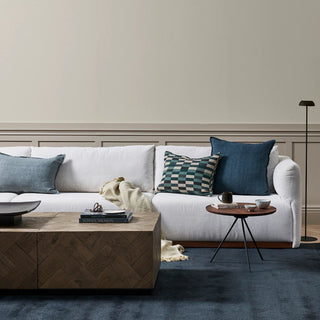 Modern living room with a white sofa, decorative pillows, and a wooden coffee table.