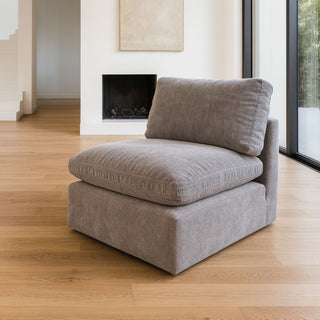 Grey upholstered chair in a modern living room with wooden floor and fireplace.