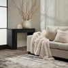 Living room with a beige sofa, fur throw, and decorative items.