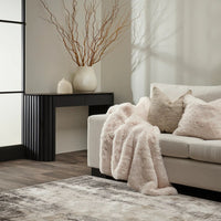 Living room with a beige sofa, fur throw, and decorative items.