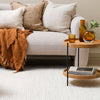 Cozy living room with a beige sofa, decorative pillows, and a wooden side table.