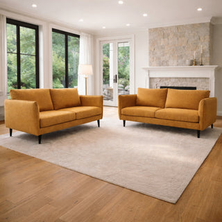 Two mustard yellow sofas in a living room with large windows and a fireplace.