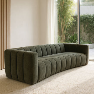 Green sofa in a modern living room with large windows and plants.