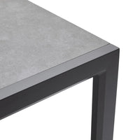 Corner of a table with gray concrete top and black metal frame on a white background