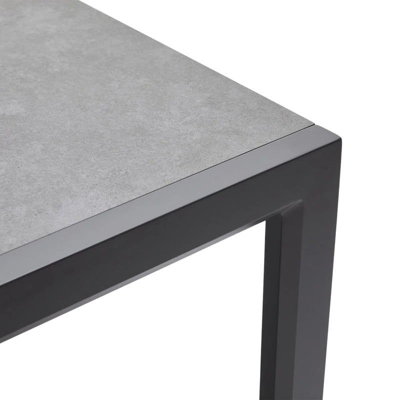 Corner of a table with gray concrete top and black metal frame on a white background