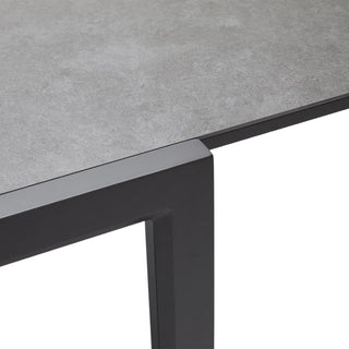 Close-up of a table with a gray concrete-like top and black metal legs on a white background