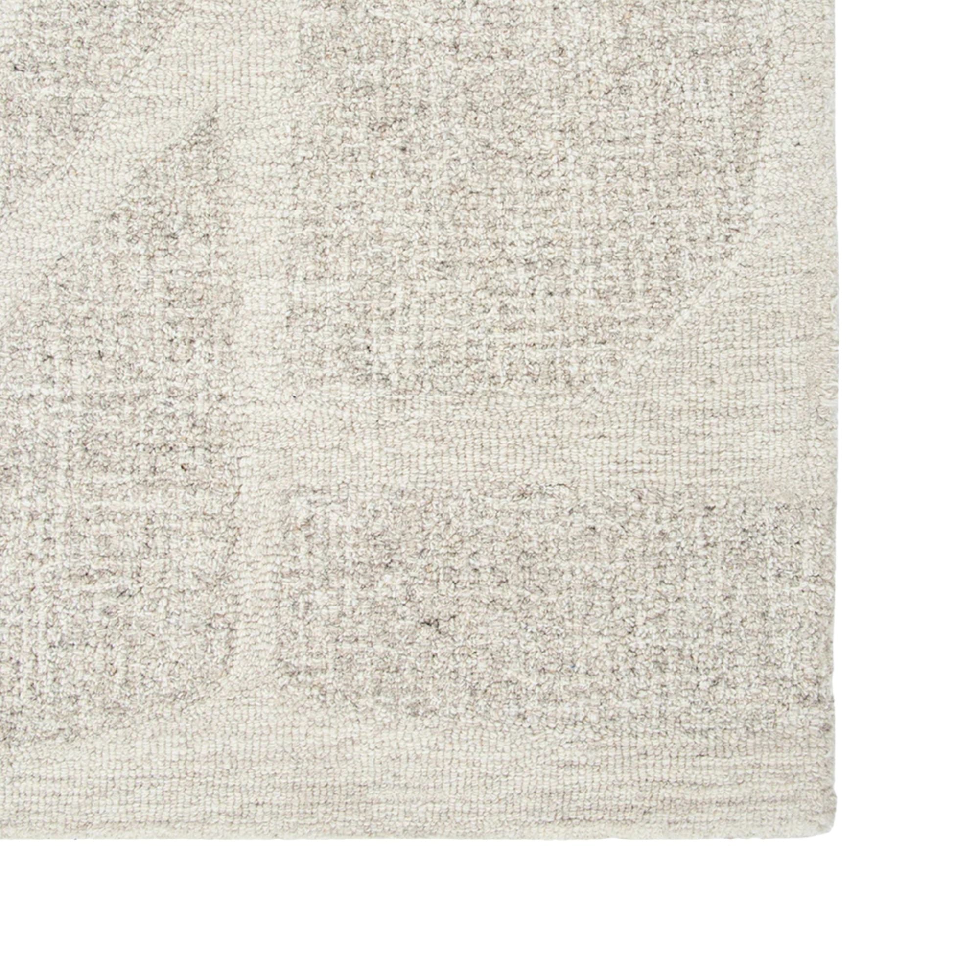 Close-up of a textured beige rug with a subtle pattern on a white background