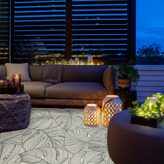 Outdoor evening setting with a couch, lanterns, and plants on a patio.