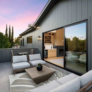 Modern outdoor patio with furniture and sliding glass door leading to a kitchen.