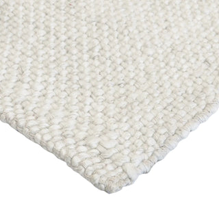 Close-up of a textured white rug corner on a white background