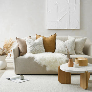Modern living room with a beige sofa, decorative pillows, and a coffee table.