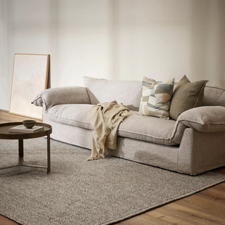 Living room with a beige sofa, coffee table, and abstract art on a white wall.