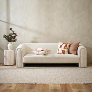 Beige sofa with decorative pillows in a minimalistic living room setting.