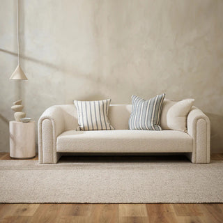 Beige sofa with striped cushions in a minimalistic living room.