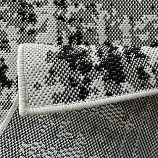 Close-up of a textured black and white rug with a folded corner.